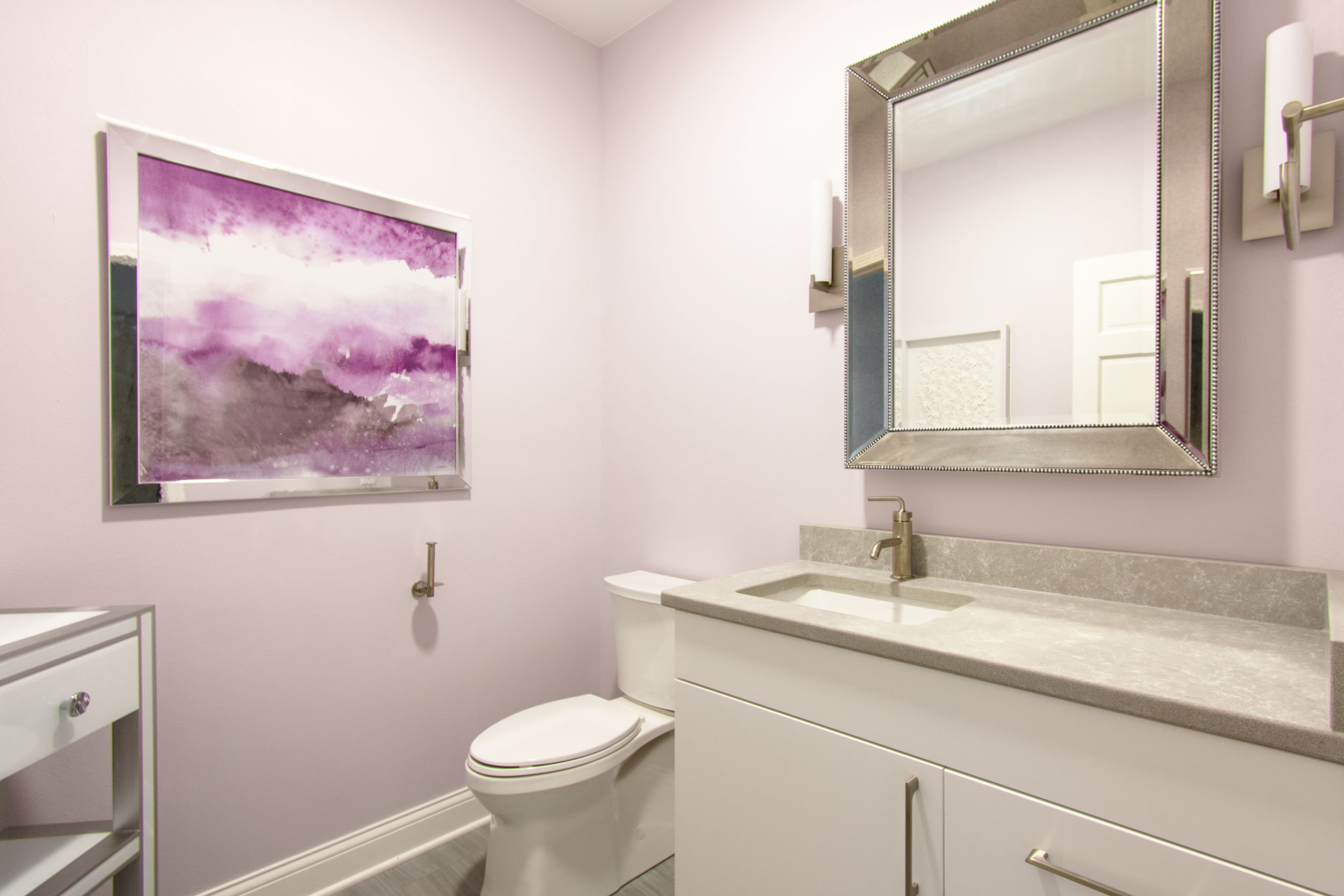 Powder bathroom with purple walls, white vanity and gray counter